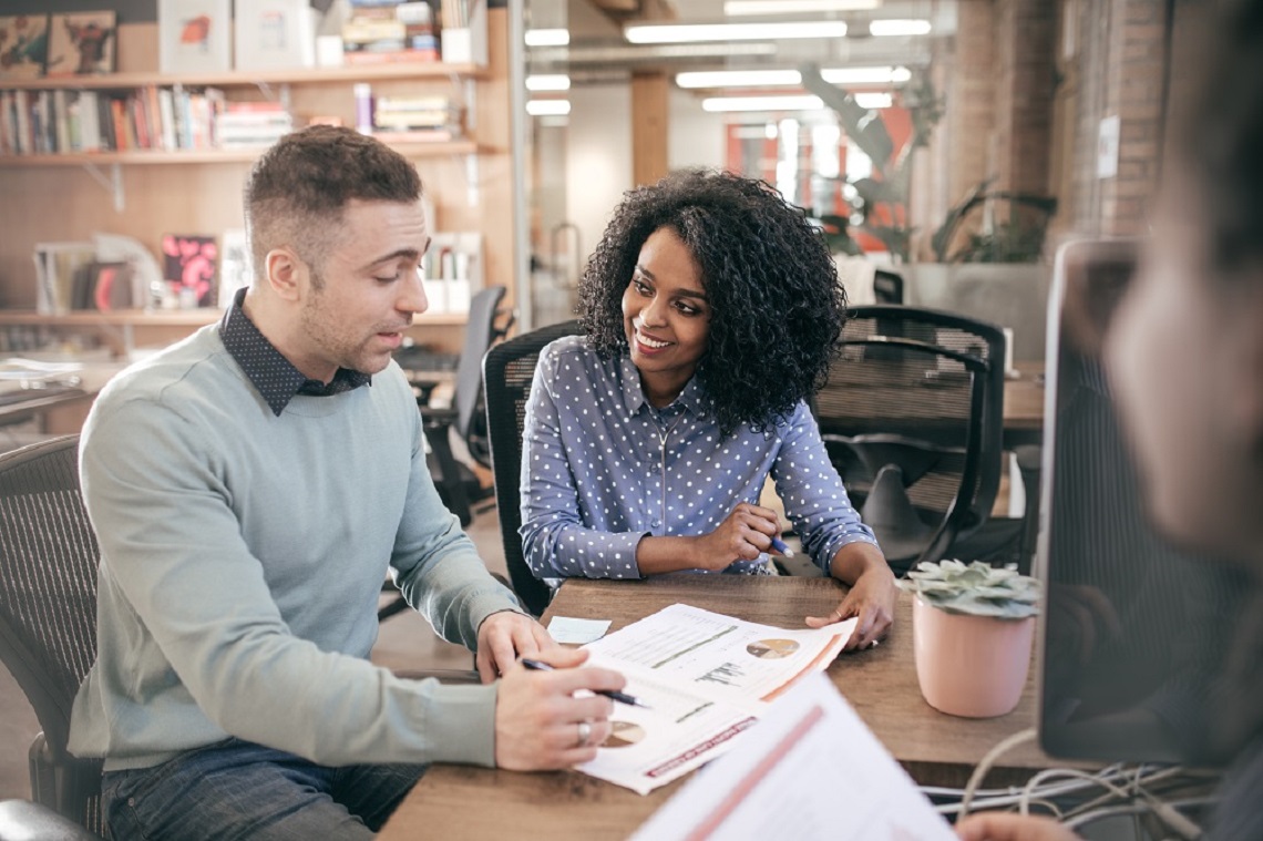 Two people smiling looking at a paper on the desk