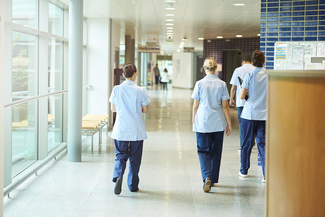 Nurses walking down a hallway in a hospital.